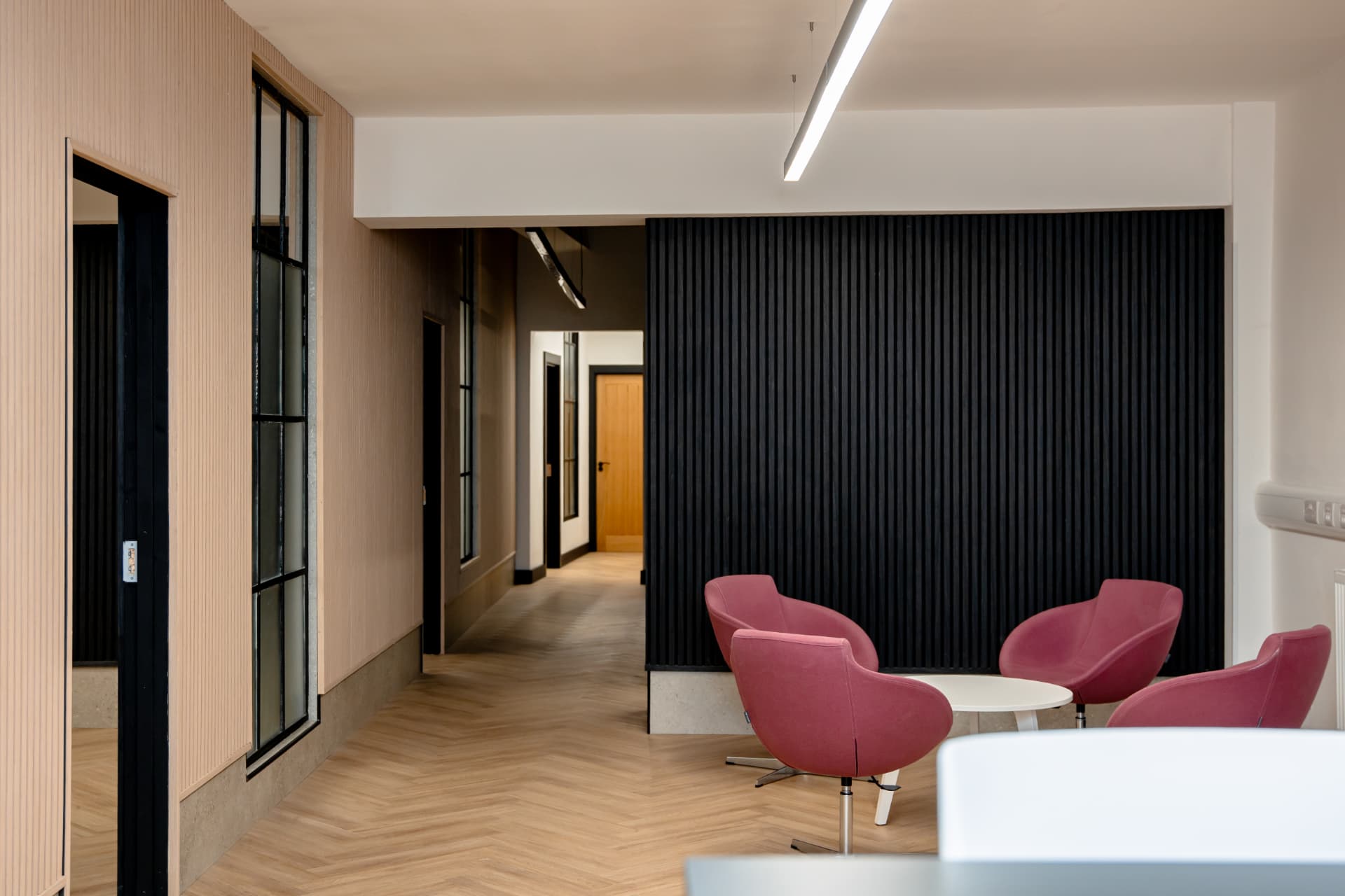 Breakout lounge at Workpoint with pink armchairs, coffee table and slatted feature wall