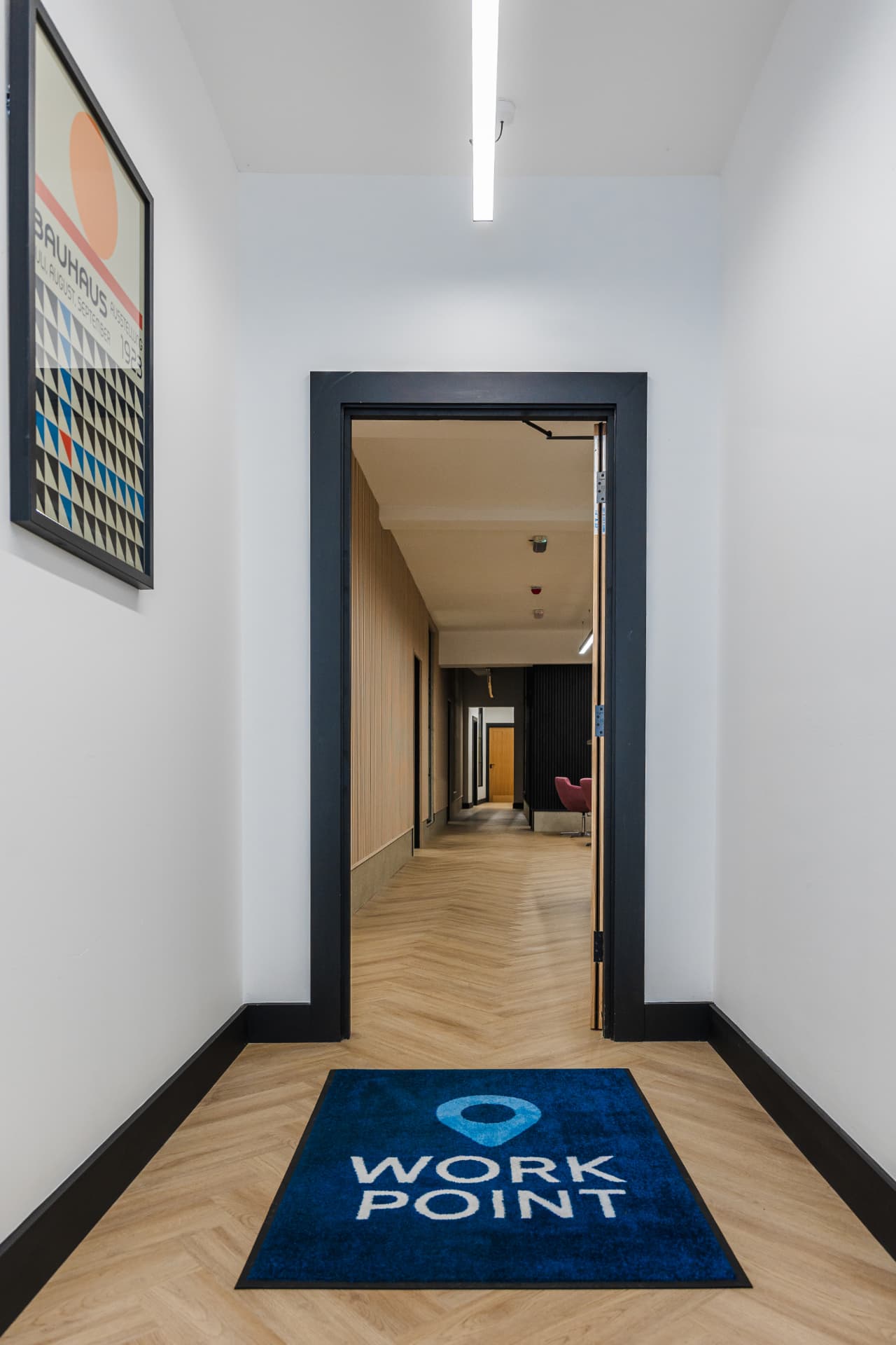 Workpoint entrance with branded floor mat, herringbone flooring and view down the corridor